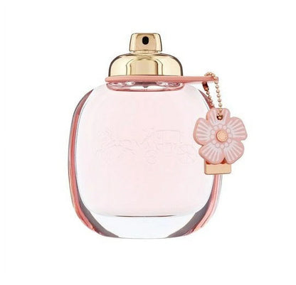 Pink perfume bottle with gold cap and flower-shaped tag on a white background