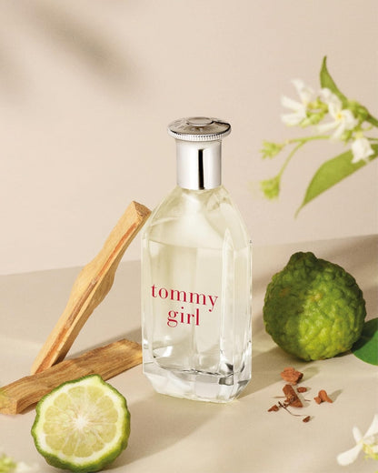 Tommy Girl perfume bottle with lime, lemon, and flowers on a beige background